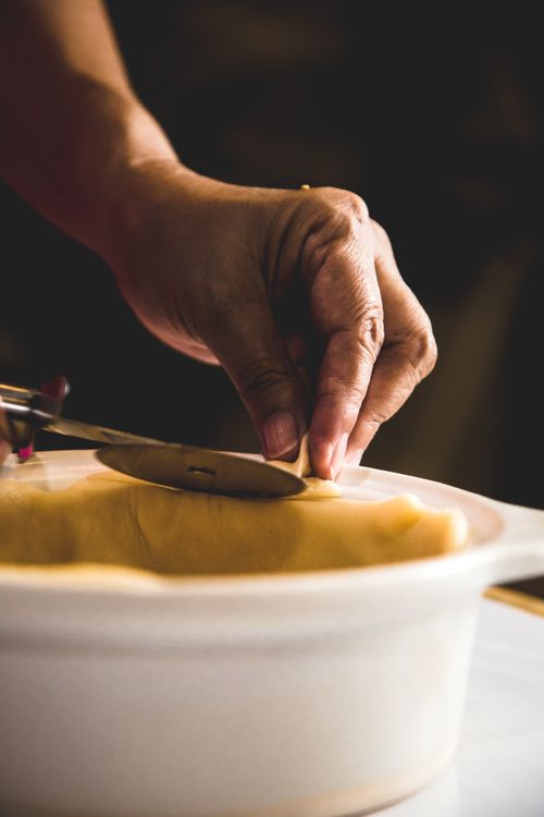 Free A close-up of hands using a cutter on pastry dough for quiche preparation. Stock Photo