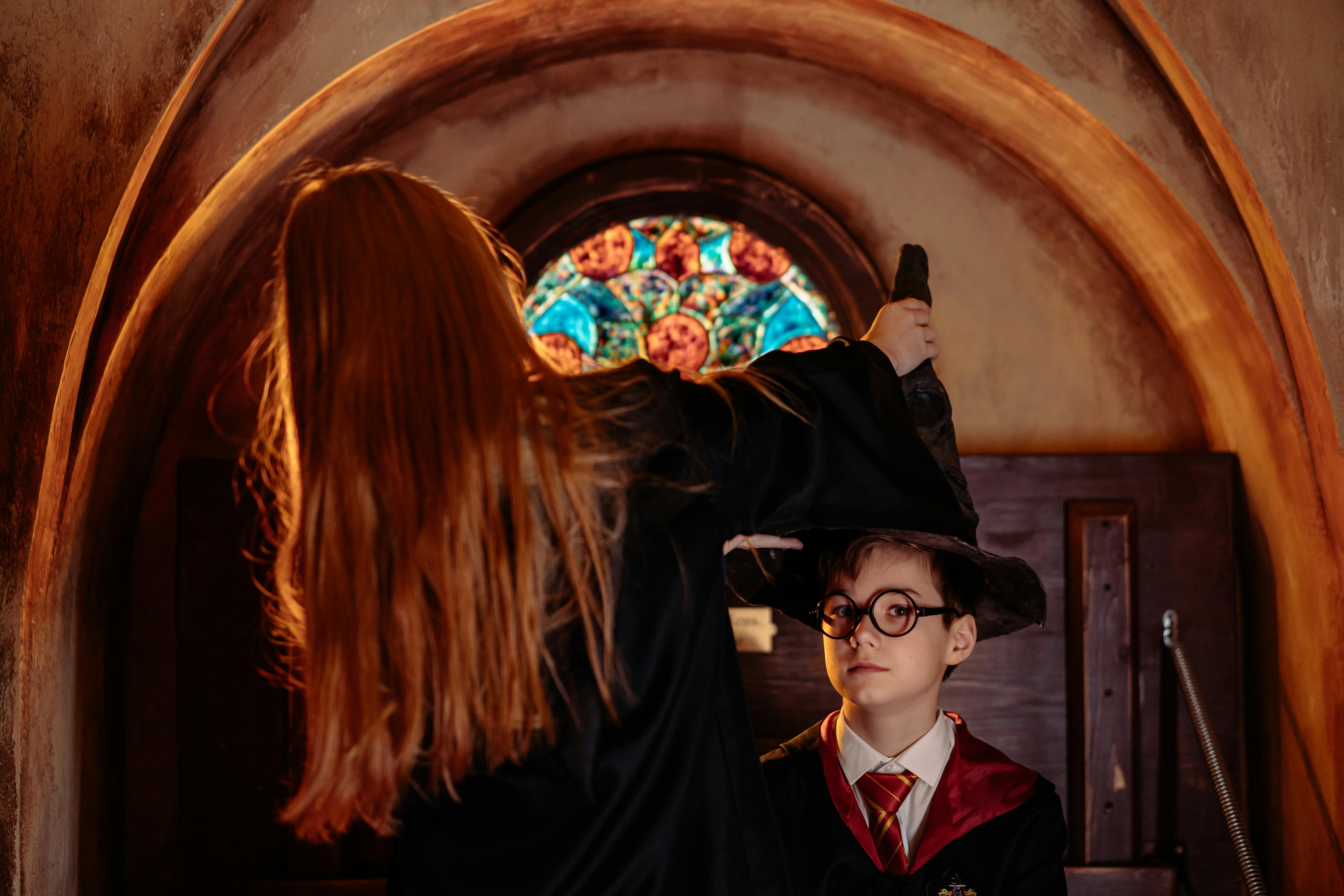 Two young wizards in robes engage in a magical setting with stained glass backdrop.