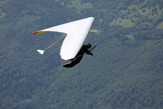 Experience the exhilarating freedom of hang gliding over lush green forests with expansive views.