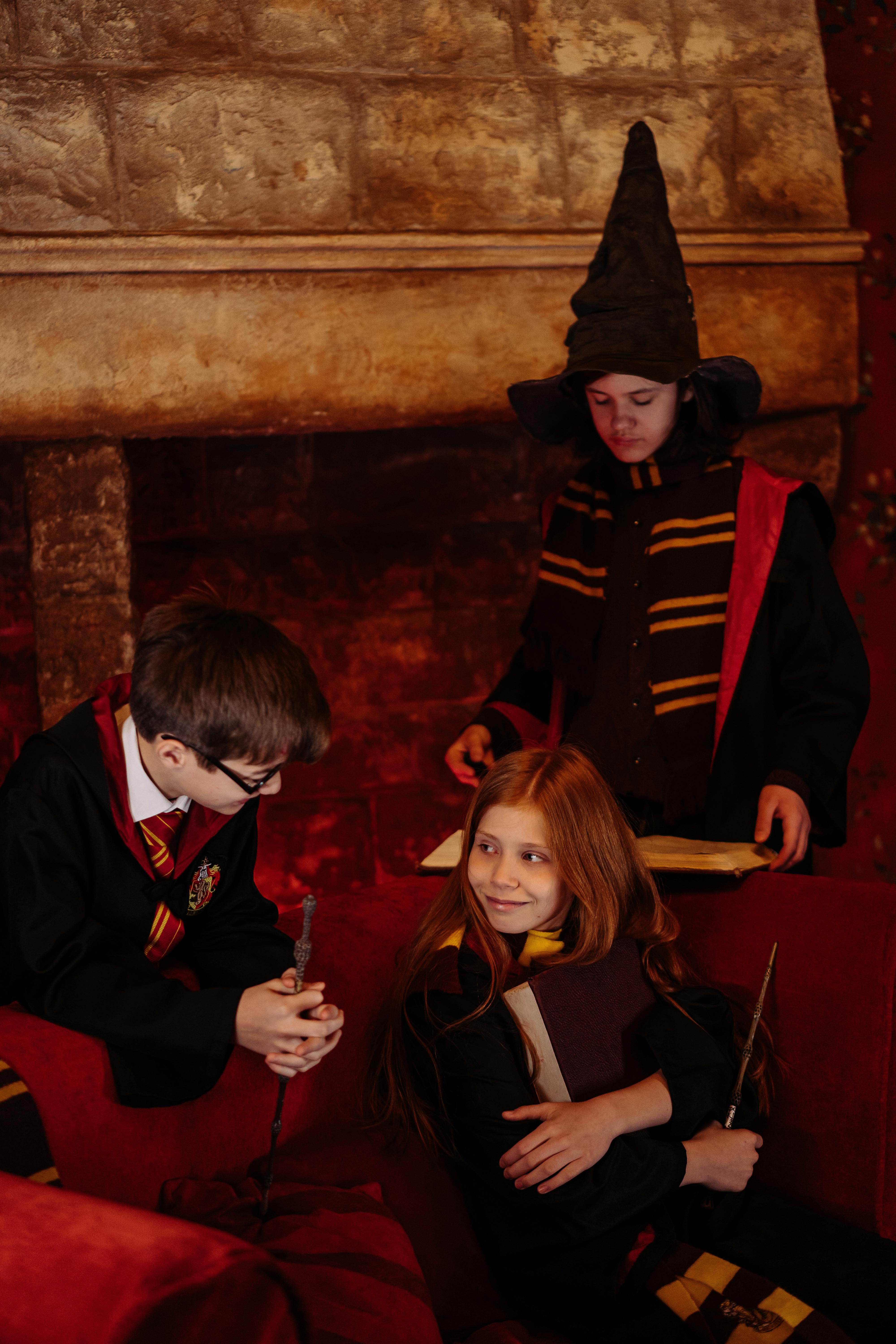 students sitting in a harry potter black robes holding a magic wands and spell book