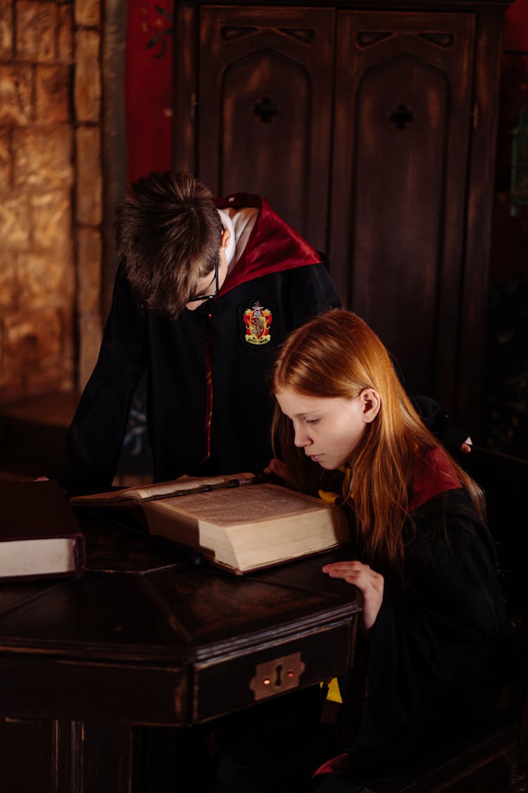 A Boy And Girl Reading A Book Together 