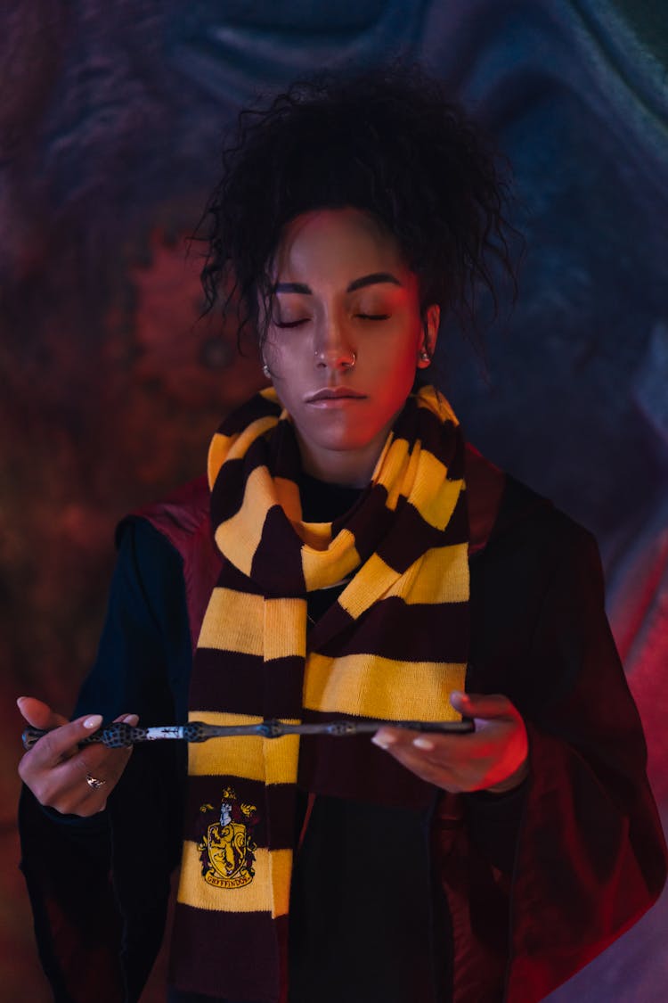 A Woman Closing Her Eyes In Yellow And Black Scarf Holding A Magic Wand