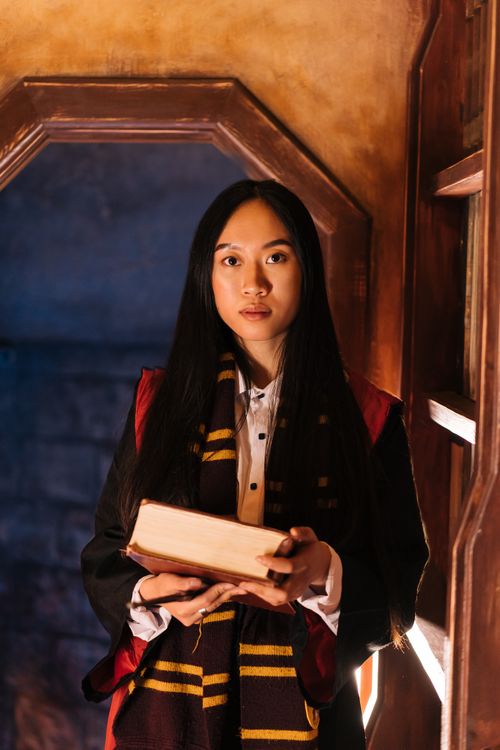 Free Young woman in a magical costume holding a book inside a mystical room. Stock Photo