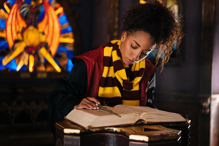 A Woman Wearing Striped Scarf Reading A Book Of Spell