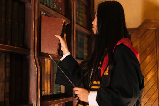 A woman in cosplay retrieves a spellbook in a fantasy library setting.