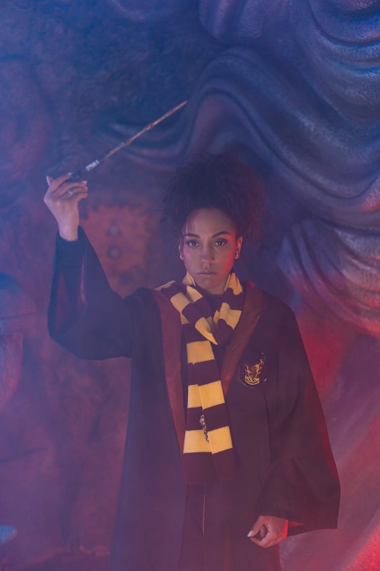 A Woman Standing In A Harry Potter Black Robe Holding A Magic Wand