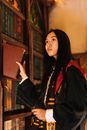A Low Angle Shot of a Person Holding a Book and a Wand