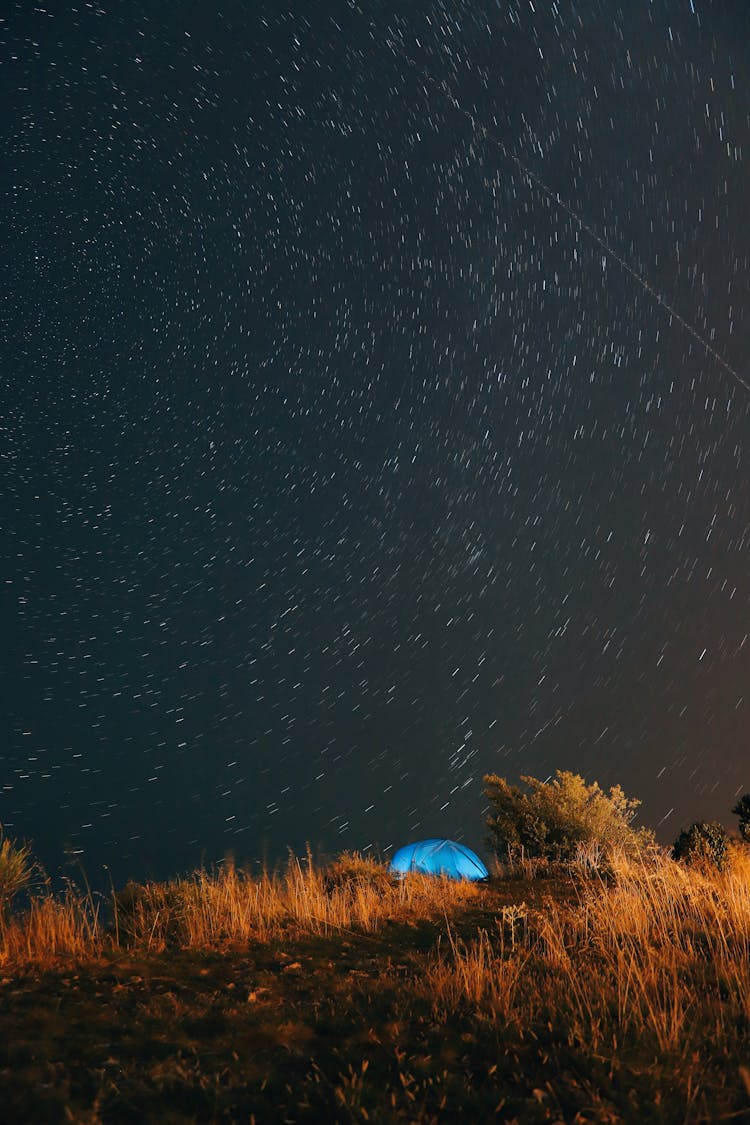 A Tent On A Hill Under A Starry Night Sky