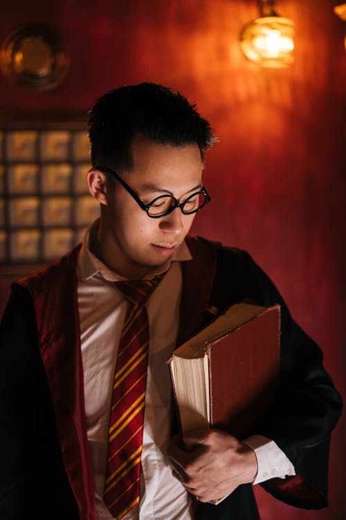 Young Man Standing in Harry Potter Black Robe Holding a Spell Book 