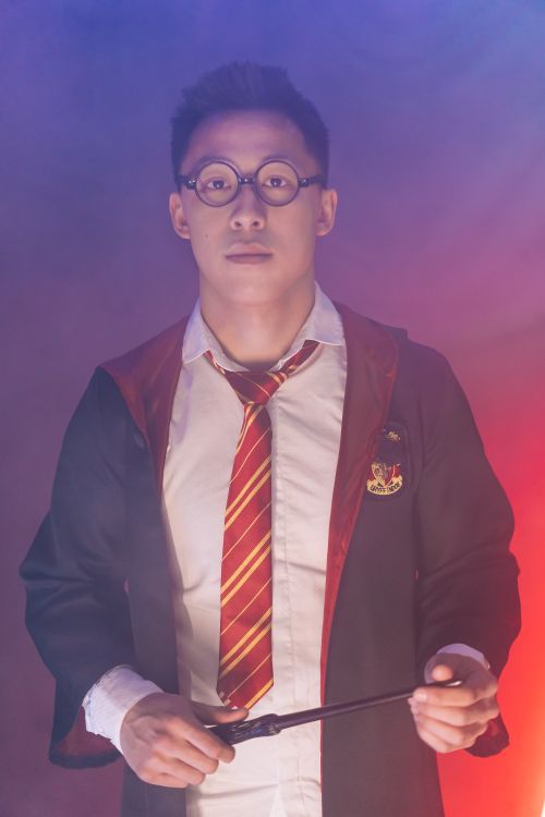 Free A man in wizard costume with glasses and a wand in a studio setting. Stock Photo