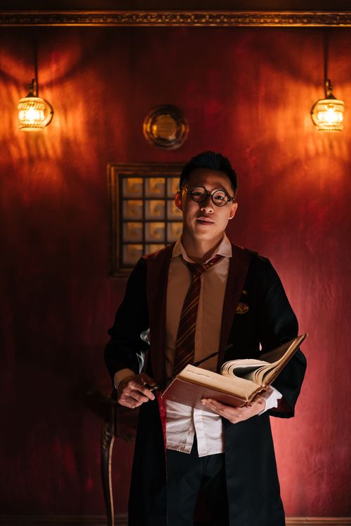Free Portrait of a man dressed as a wizard in a dimly lit room holding an open spellbook. Stock Photo