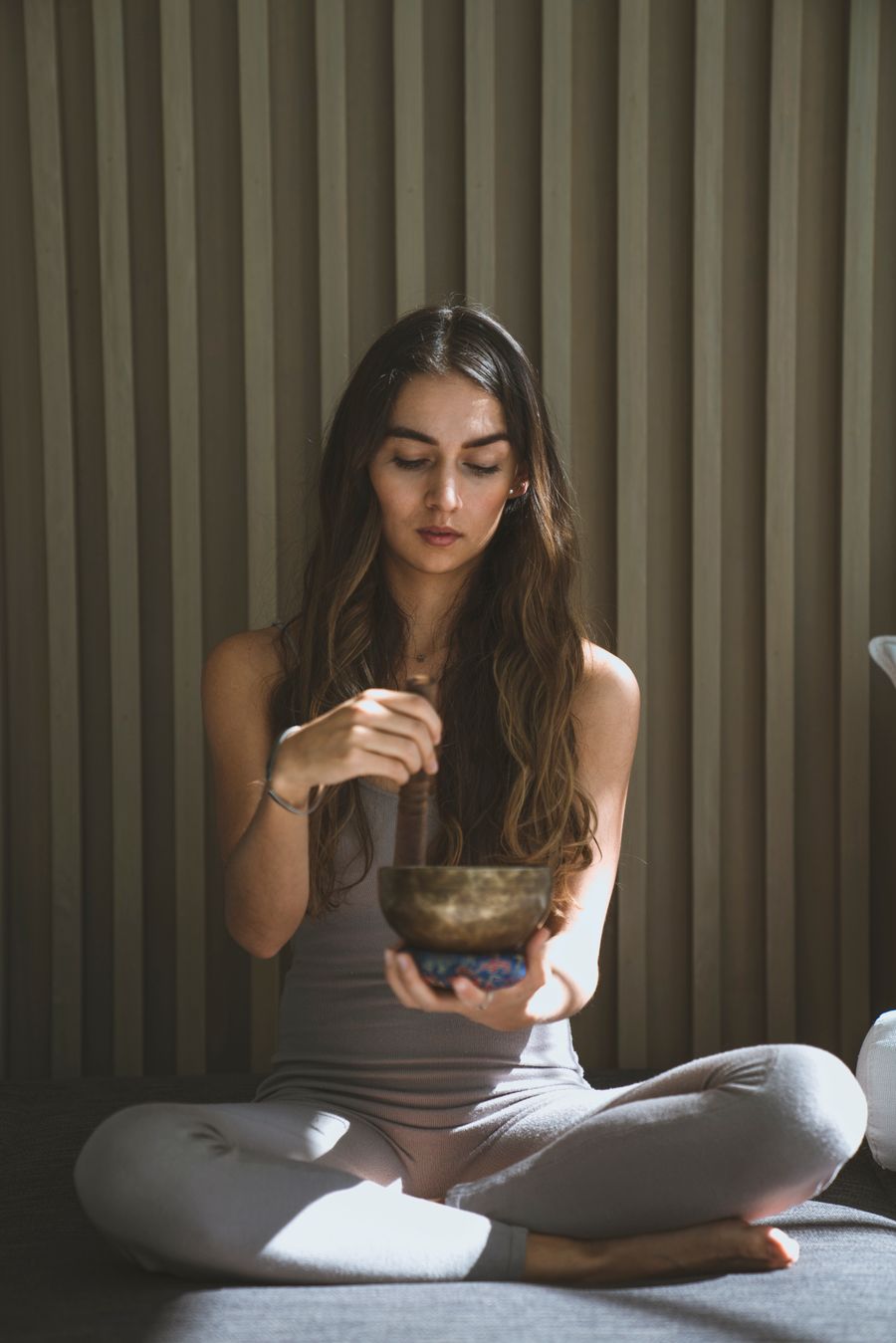 Practitioner holding a Tibetan healing bowl above a resting client