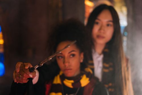 Free Two women holding a wand creating a magical fantasy atmosphere indoors. Stock Photo