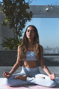 Peaceful meditation scene with a woman practicing yoga outdoors in a serene setting.