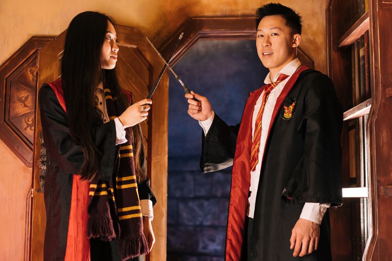 Two children dressed as a witch and wizard holding crossed magic wands
