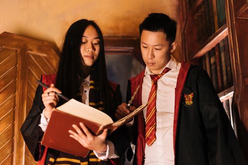 Free Two people in wizard costumes reading from a book indoors. Magical theme. Stock Photo