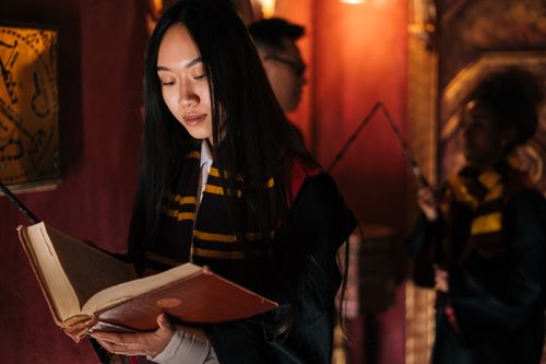 Free Three cosplayers dressed as witches in a magic-themed setting, engaged with spellbooks. Stock Photo