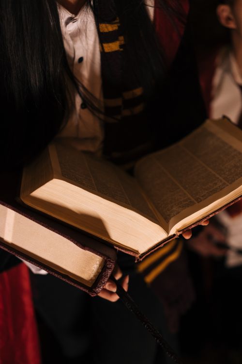 Free Close-up of an open book held by a person in a dimly lit environment, evoking mystery. Stock Photo