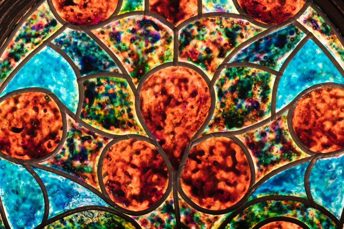 Free Colorful stained glass window with intricate floral patterns and vivid colors. Stock Photo