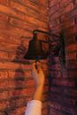 Close-Up Shot of a Person Ringing a Bell Hanging from the Brick Wall
