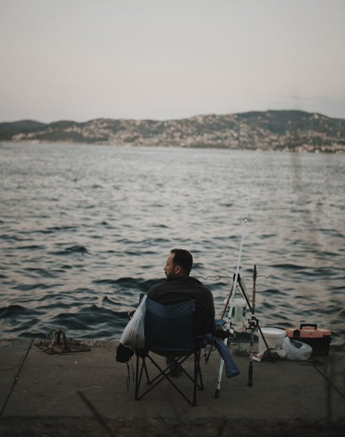 Angler Sitting in Chair by Sea