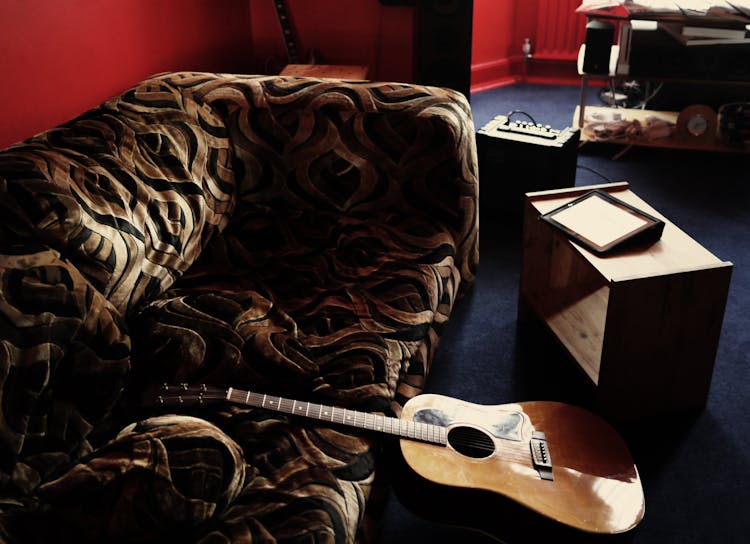 Brown Acoustic Guitar Leaning On Brown Velvet Couch