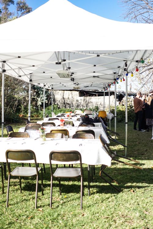 Free Sunny outdoor setting with tables, chairs, and white tent for events. Stock Photo