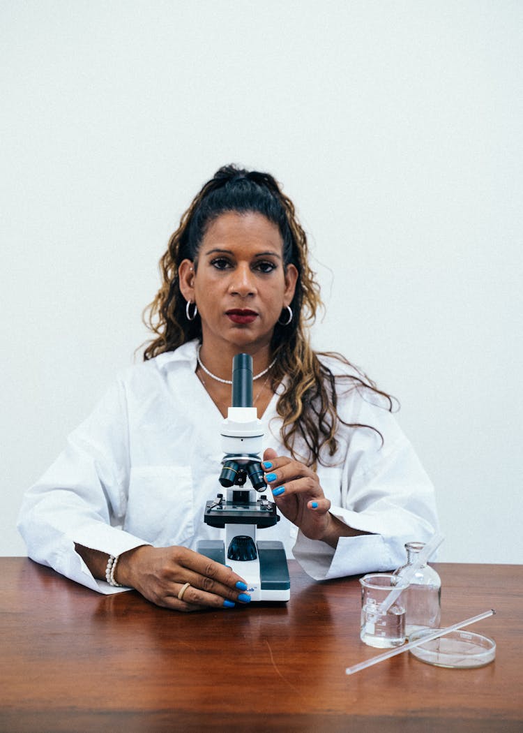 A Woman Holding A Microscope On A Table