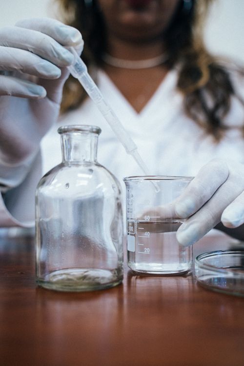 Free Chemist using a pipette and beakers for a laboratory experiment, wearing gloves. Stock Photo