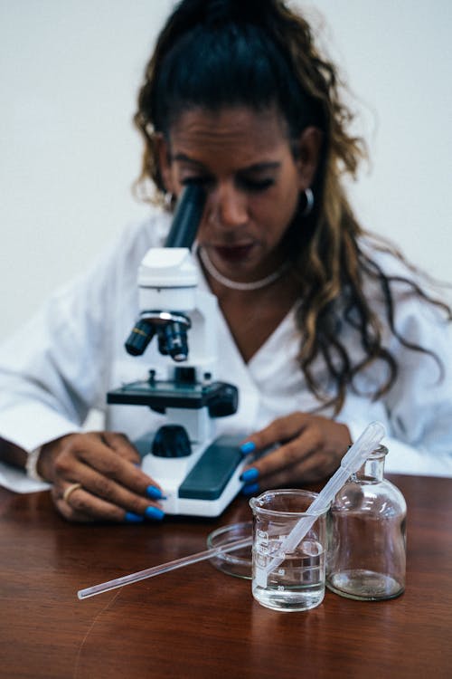 Free Woman in Lab Gown Looking at the Microscope  Stock Photo