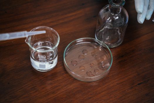 Hands adding a testing drop into a glass of water