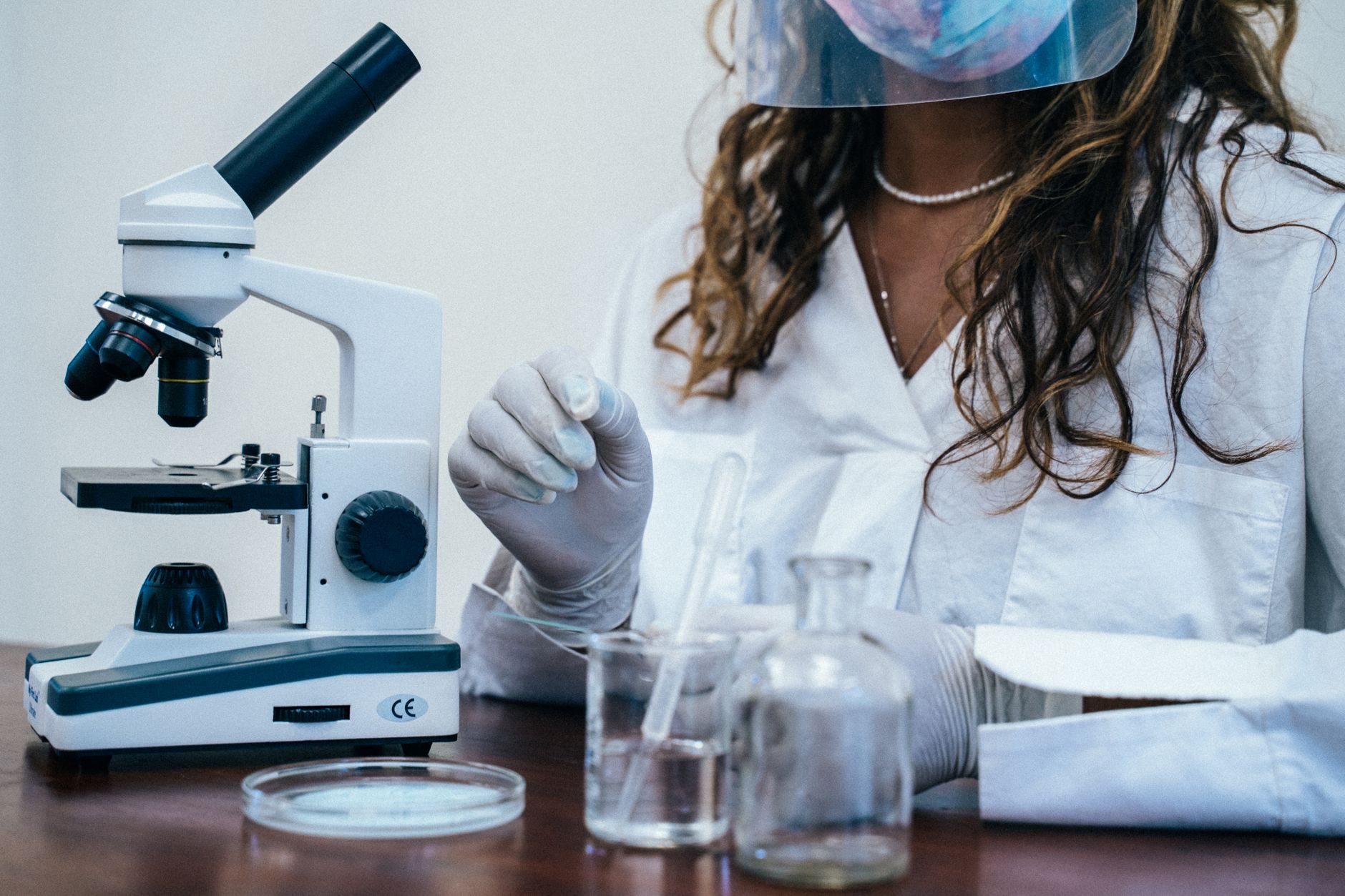 Woman scientist in lab coat using microscope with laboratory equipment.