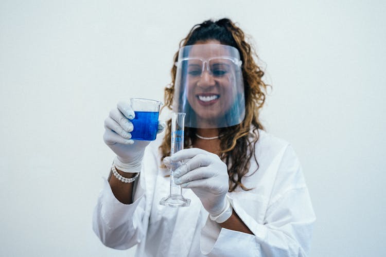 Smiling Woman Pouring Blue Liquid On Graduated Cylinder 