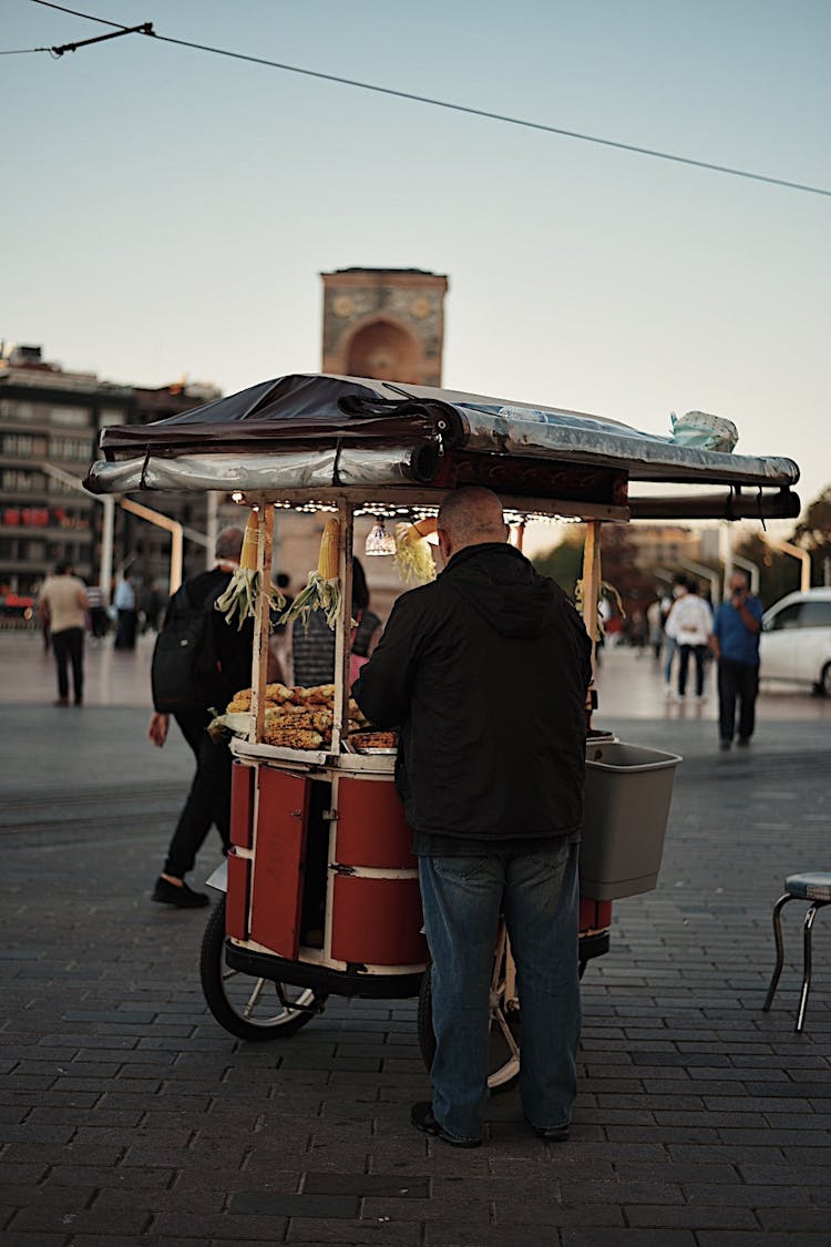 Man Selling Food From A Stall On Wheels On A Square In City 