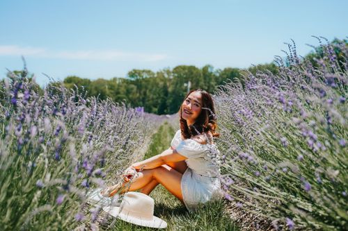 Free A joyful woman sits in a lavender field on a sunny day, embracing nature. Stock Photo
