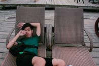 Man Wearing Green Shirt and Black Shorts Laying on Lounger