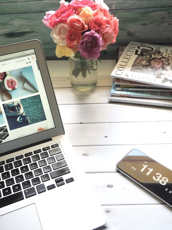 Macbook Air，花束和白色桌上的雜誌