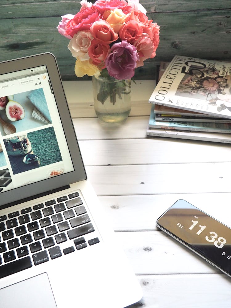 Macbook Air, Flower Bouquet And Magazines On White Table