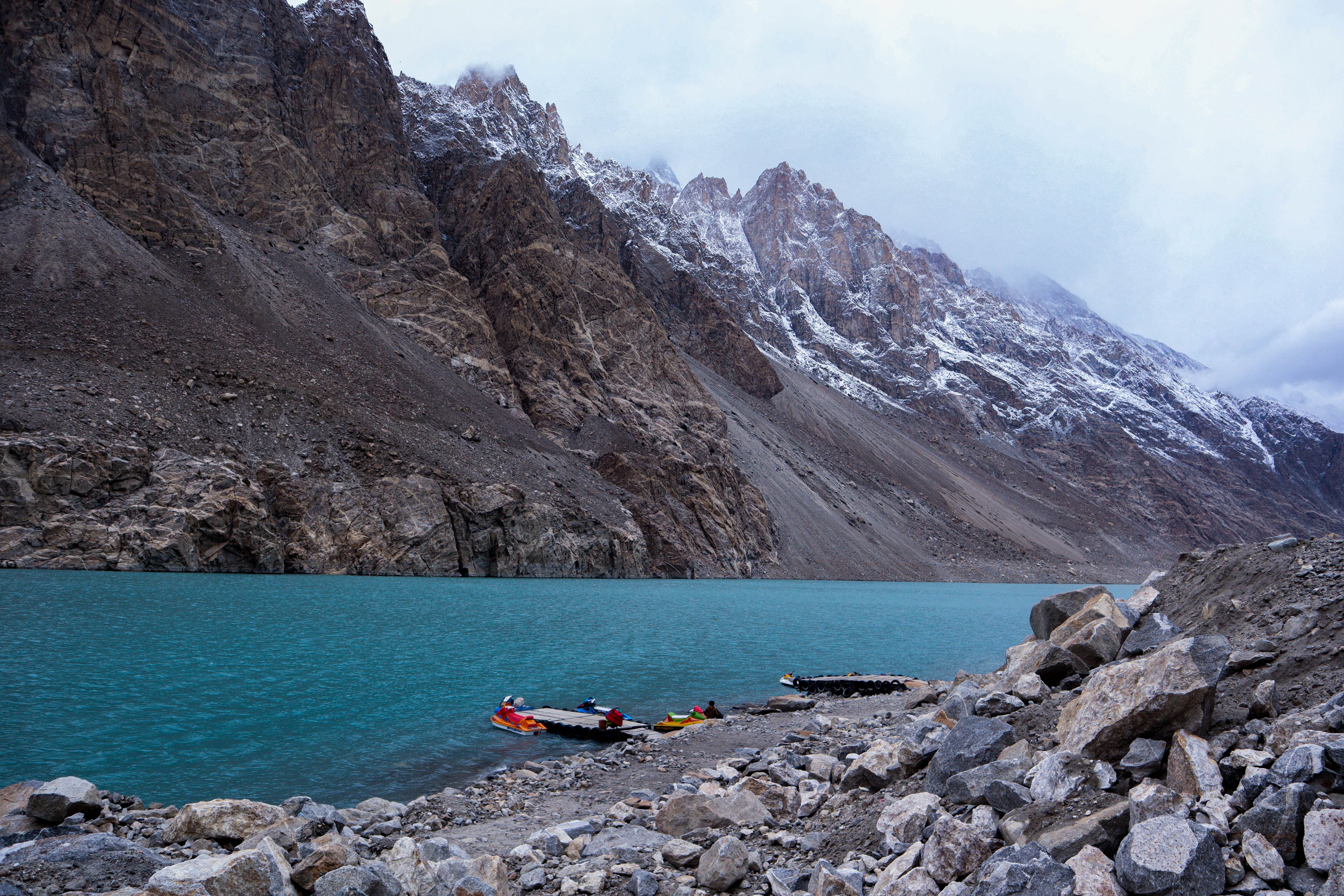 Discover the breathtaking view of serene turquoise lake with snow-capped mountain peaks in a tranquil setting.