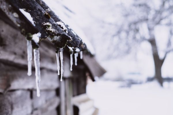 Icicles hanging from a snowy wooden roof edge