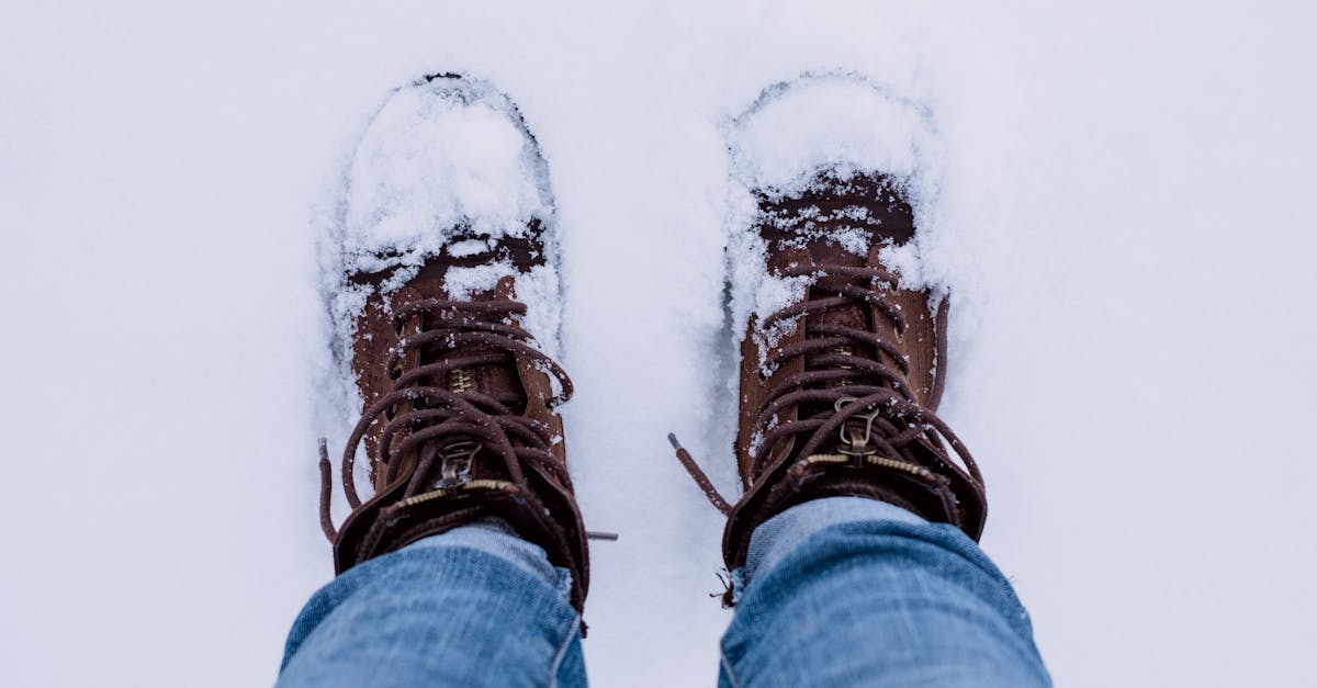 Person Wearing Brown Boots and Blue Denim Jeans Standing on Snow