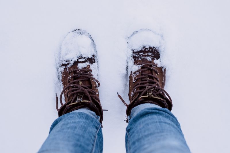Brown boots and jeans standing on snow