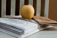 A close-up of an apple on tied documents and a notebook, evoking a cozy study vibe.