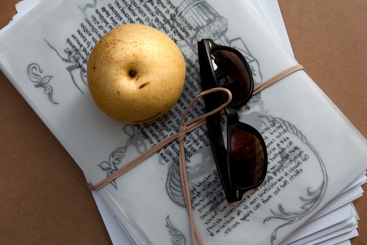 Sunglasses And An Apple On A Bundle Of Paper