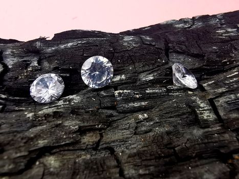 Close-up of three diamonds placed on rustic charcoal, showcasing contrast and brilliance.