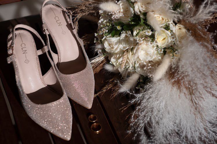 Gold Rings Beside Wedding Shoes