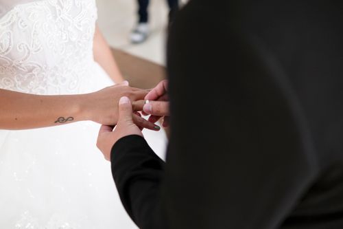 Free A groom places a ring on the bride's finger during a wedding ceremony, capturing a timeless moment. Stock Photo