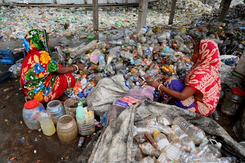 Woman Sitting on Recycled Trash of Plastic Bottles 