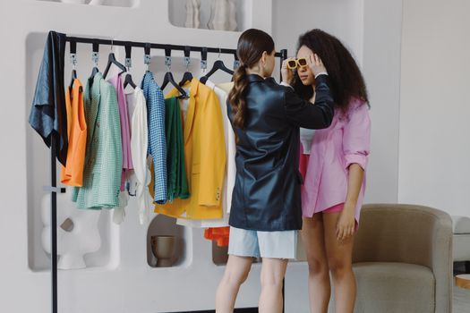 Fashion stylist assists client in a vibrant wardrobe fitting, ensuring perfect accessory choices.