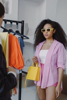 Woman in vibrant outfit shopping at a boutique with colorful fashion displayed.